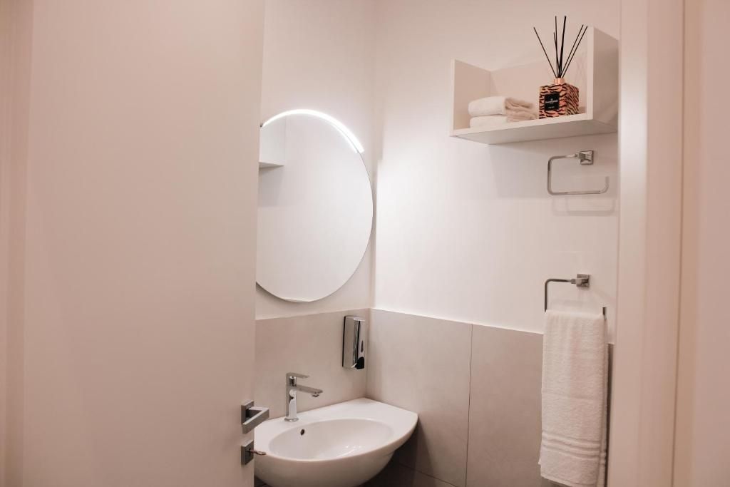 A modern bathroom with a round mirror, a sink, and a towel rack.