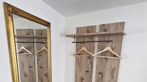 Une pièce dotée d’un grand miroir, de panneaux muraux en bois, d’un banc et d’une poubelle.