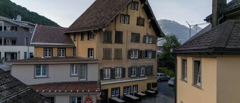 A multi-story building with a central courtyard, featuring a restaurant named 'Adler Brau Central' with outdoor seating.