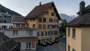 Un edificio de varios pisos con un patio central, que cuenta con un restaurante llamado 'Adler Brau Central' y mesas al aire libre.