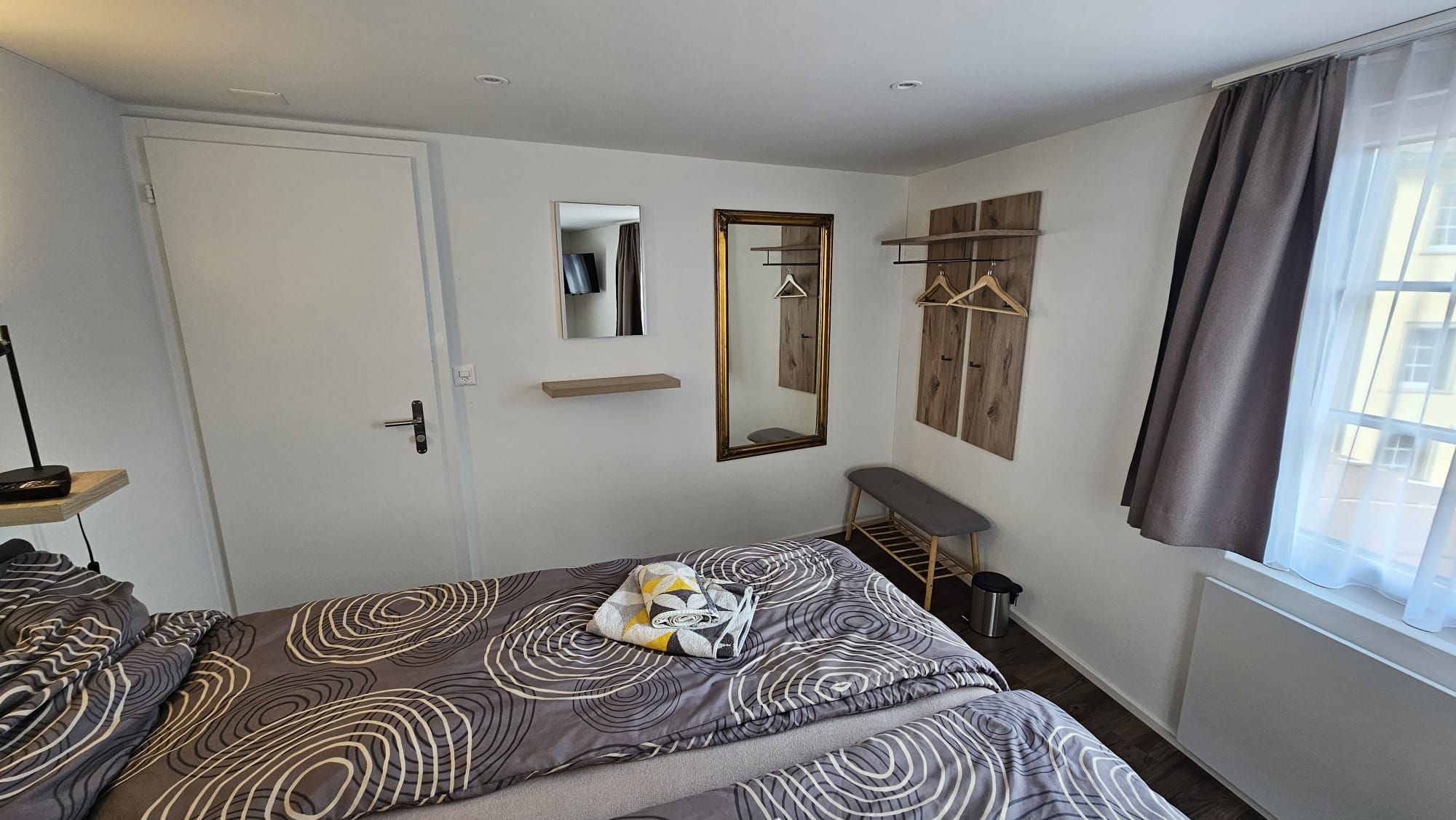 Comfortable private double room with fresh towels, TV, and natural light.
