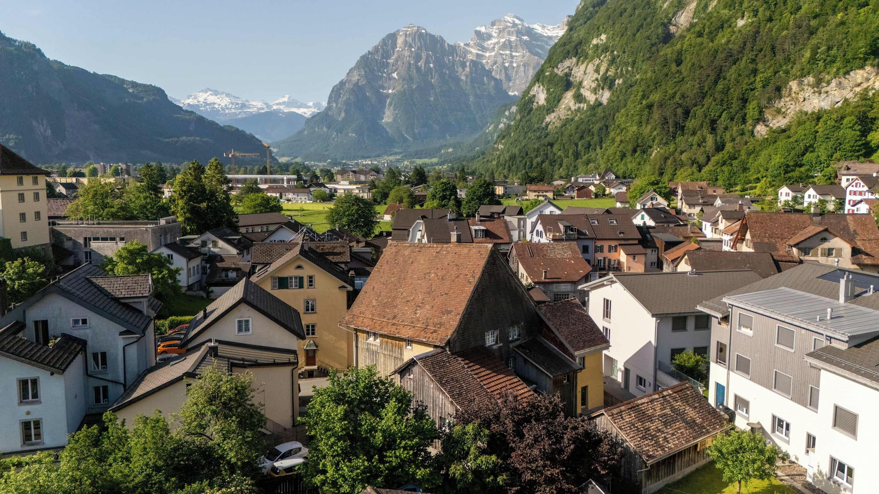 Una cittadina dall'architettura tradizionale, circondata da montagne e vegetazione.