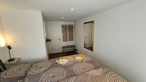 A bedroom with a bed, bedside table, lamp, and a mirror on the wall.