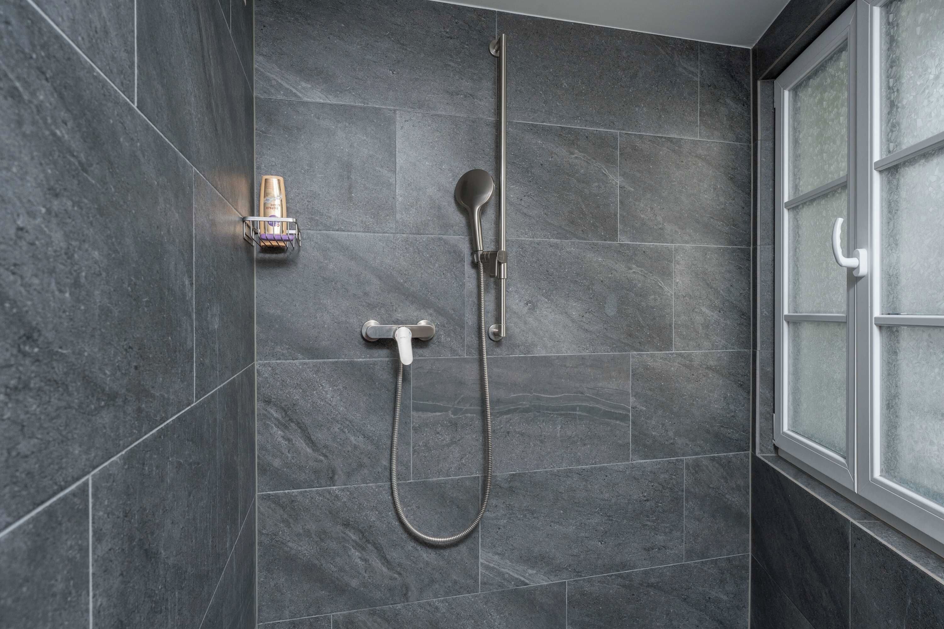 Eine Dusche mit Handbrause und Wandarmatur.