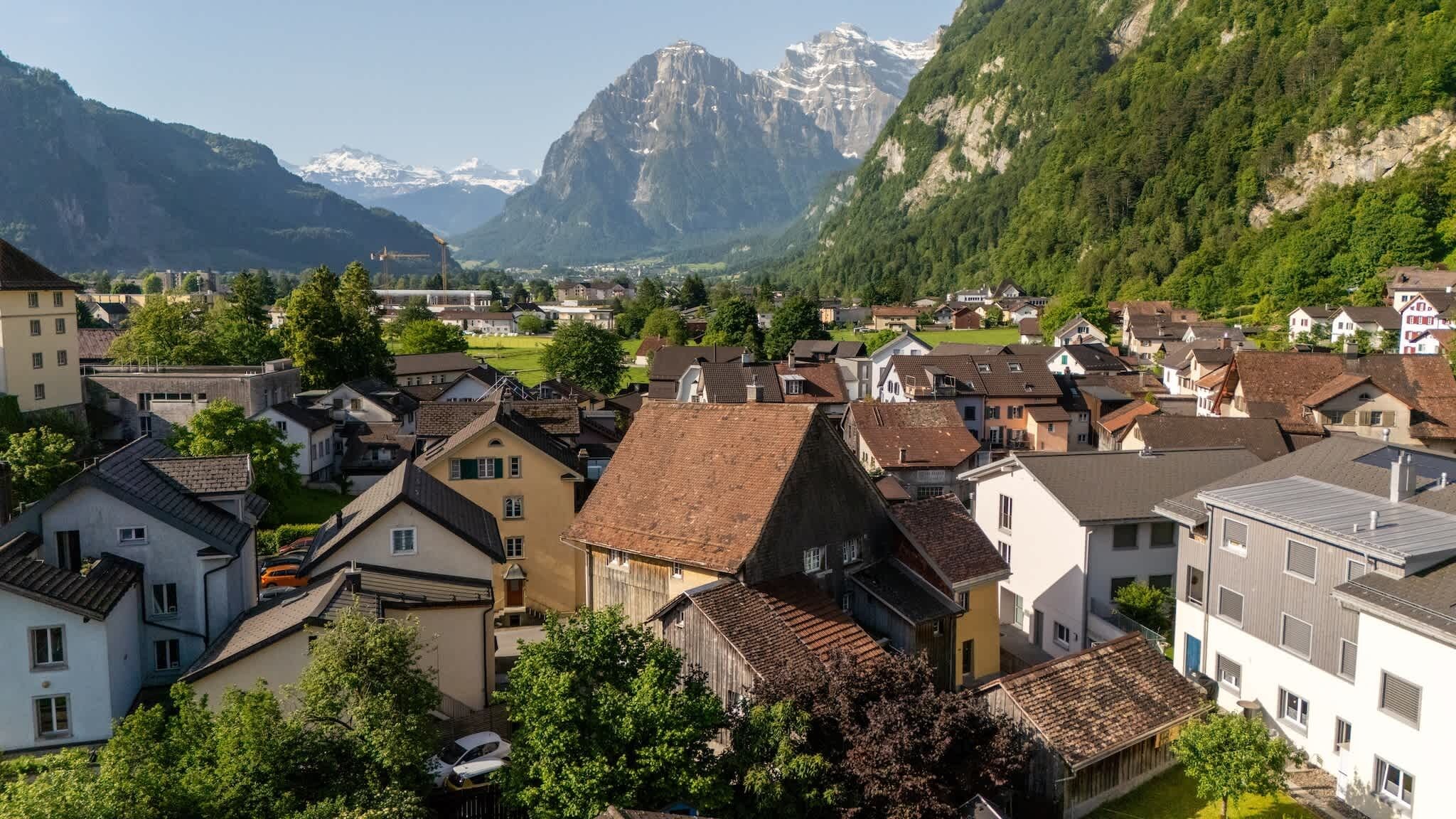 A town with traditional architecture, surrounded by mountains and greenery.