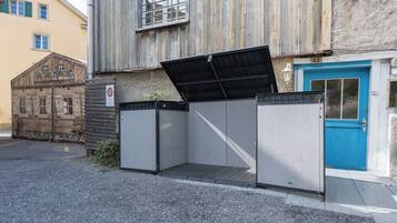 A building with a blue door, a metal fence, and a wooden structure with heart-shaped windows.