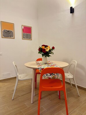 A dining area with a round table, four chairs, a vase with flowers, and two framed artworks on the wall. - Your elegant retreat in Pisa, in the heart of Tuscany (Pisa)