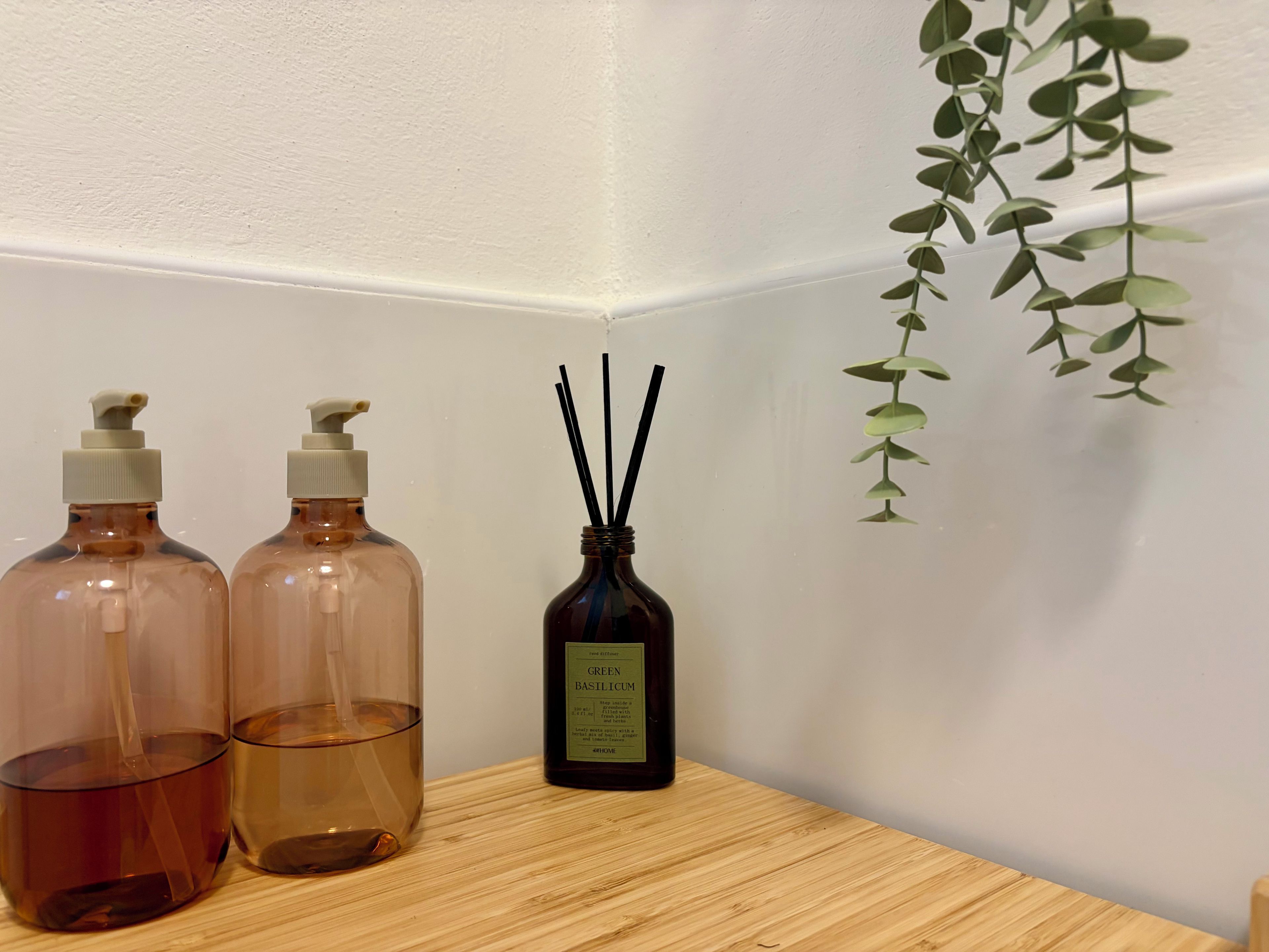 Two amber-colored bottles with pumps, a dark brown bottle with a label, and a clear glass with a liquid on a wooden surface.