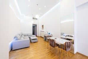 Uma sala de estar moderna com sofá, mesa de jantar com cadeiras e um espelho grande.