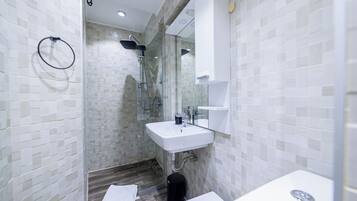 A modern bathroom with a glass-enclosed shower, a white sink, and a mirror above it.