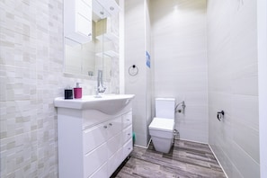 A modern bathroom with a white sink, mirror, and toilet.