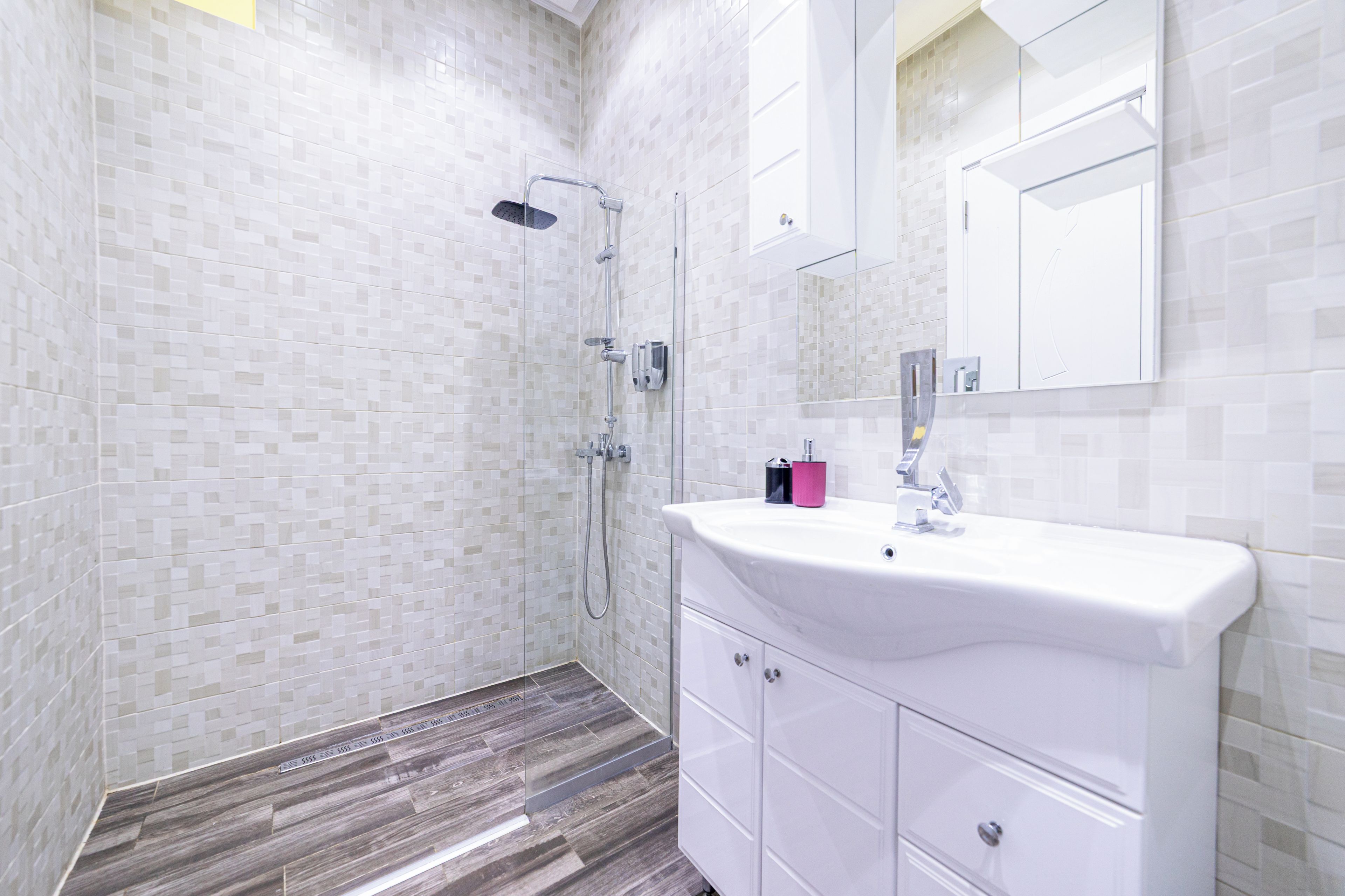 A modern bathroom with a shower, a sink, and a mirror.