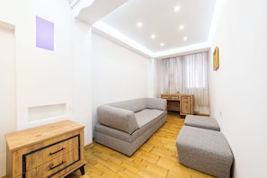Una sala de estar moderna con un sofá, un reposapiés, un mueble de madera y un escritorio con una silla.