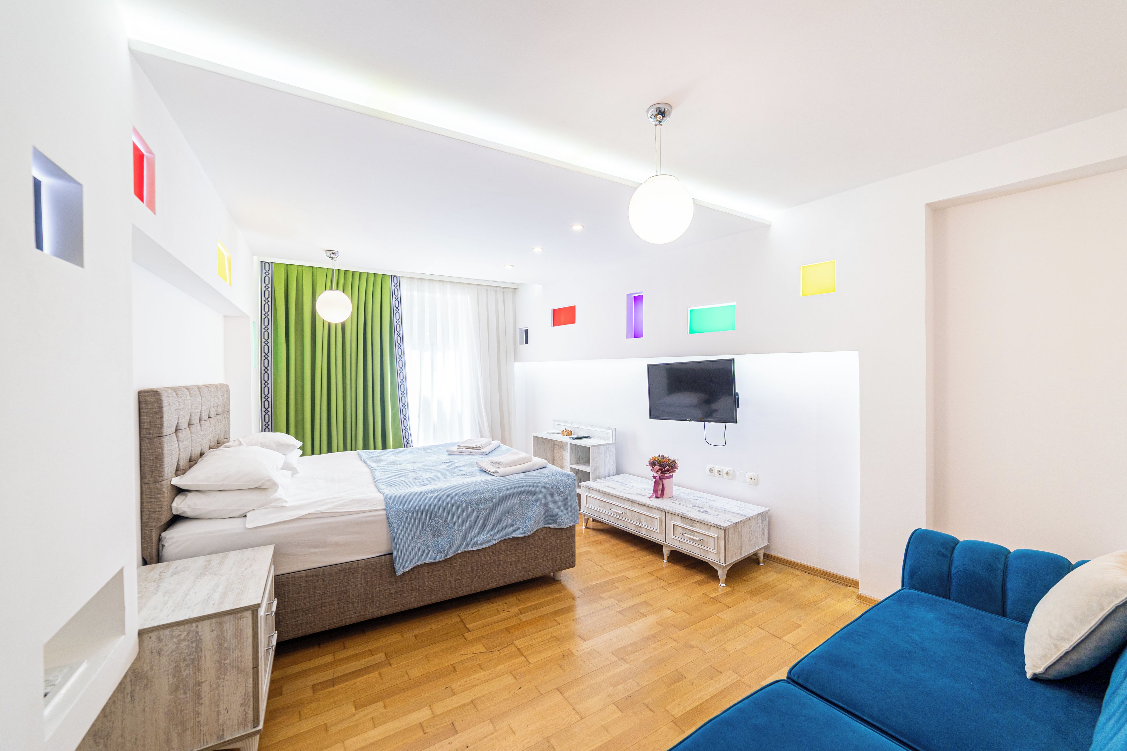 A modern bedroom with a bed, a TV, a sofa, and a small table.