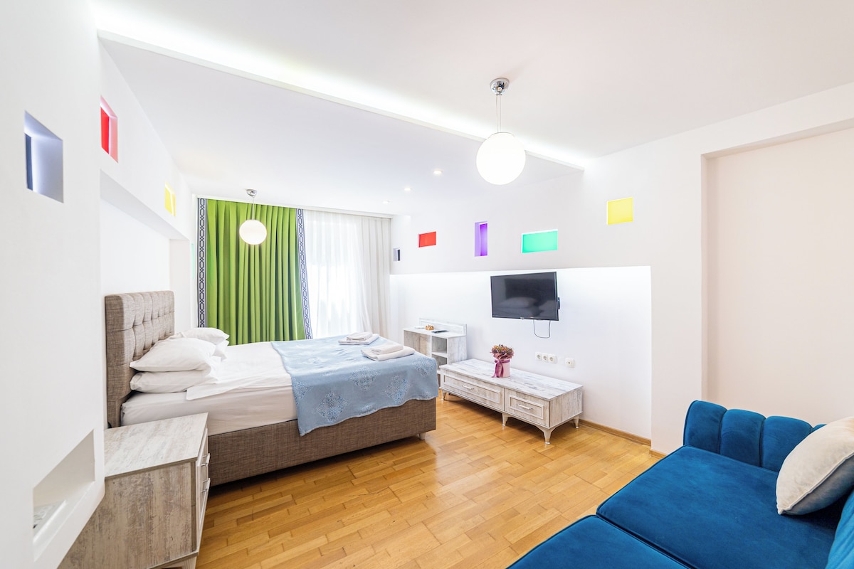 A modern bedroom with a bed, a TV, a sofa, and a small table.