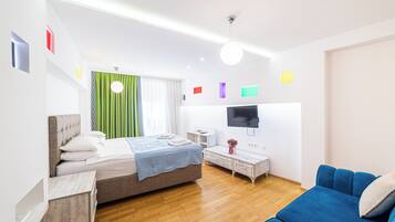 A modern bedroom with a bed, a TV, a sofa, and a small table.