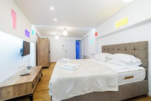 Habitación de hotel con cama, mesita de noche, armario y vista al pasillo.