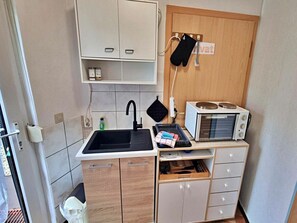 A compact kitchen with a sink, cabinets, a microwave, and a hanging pot rack. - Holiday Apartment Seahorse (Heringsdorf)