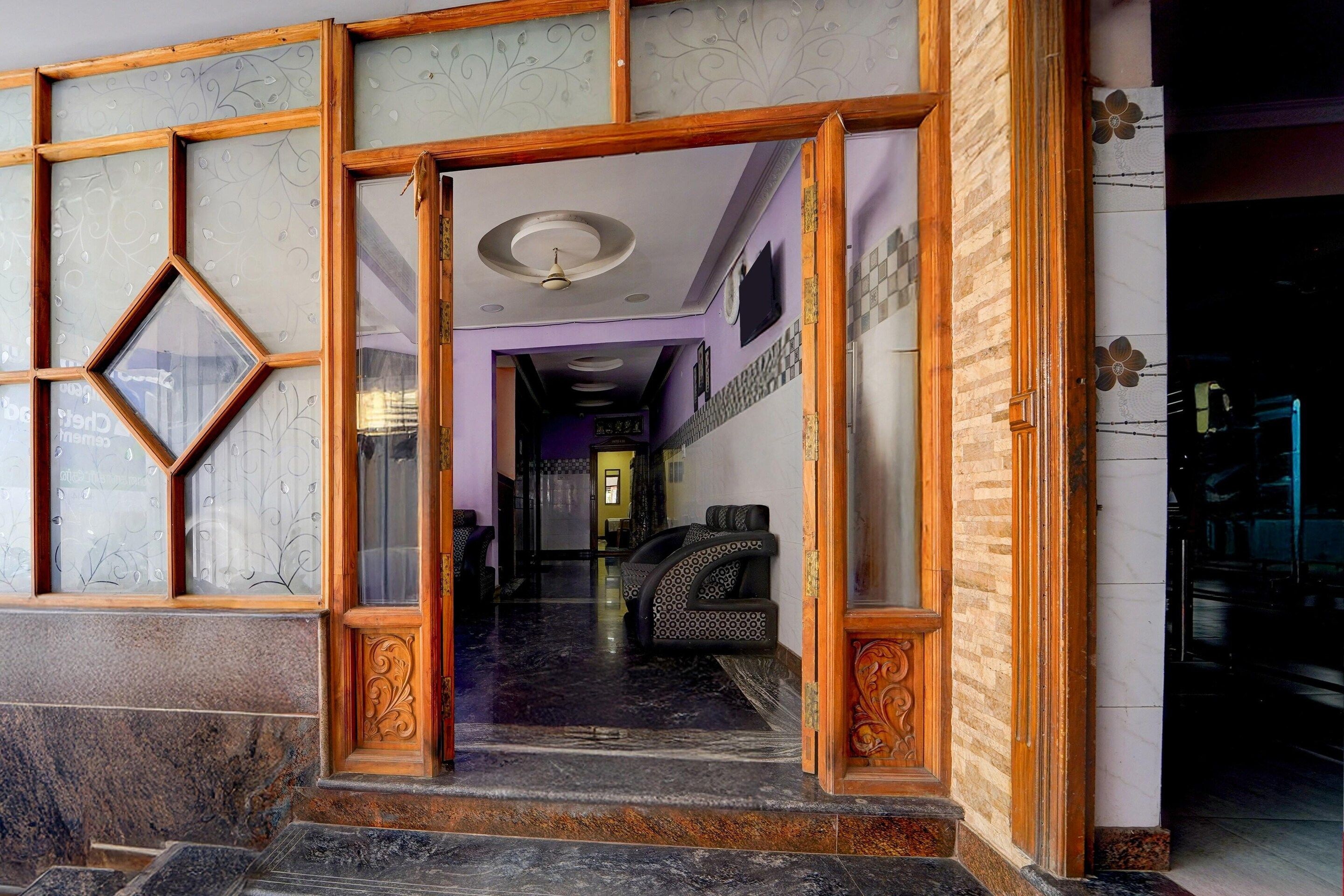 A hotel entrance with a wooden frame, a marble floor, and a staircase leading to the interior.