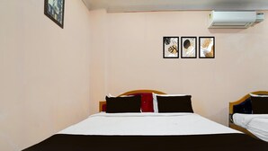 A hotel room with a bed, a nightstand, and an air conditioning unit. - Deluxe kk Residency (Karaikal)