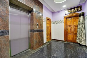 An elevator with a digital display, a wooden door, and a patterned curtain.