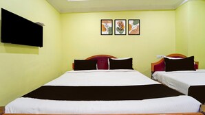 A hotel room with two beds, a flat-screen TV mounted on the wall, and three framed artworks above the beds. - Deluxe kk Residency (Karaikal)