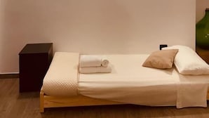 Ein Einzelbett mit Kopfteil, eine Wand-Klimaanlage und zwei Wandleuchten.