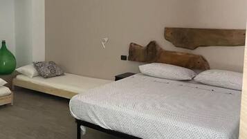 Un dormitorio con una cama, un banco, un jarrón verde y una alfombra a rayas.