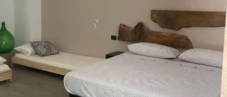 Une chambre à coucher avec un lit, un banc, un vase vert et un tapis à rayures.