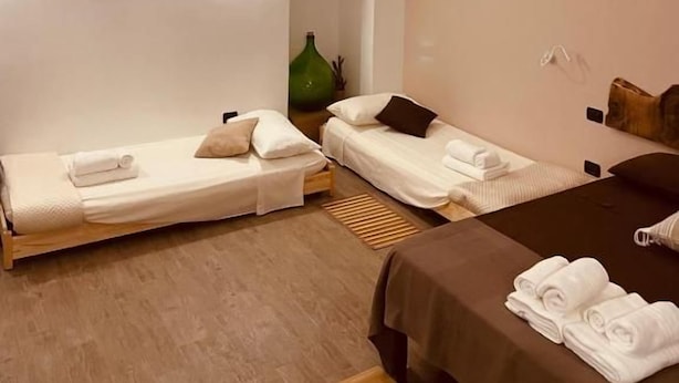 Ein Hotelzimmer mit zwei Einzelbetten, einem großen Spiegel und Holzboden.