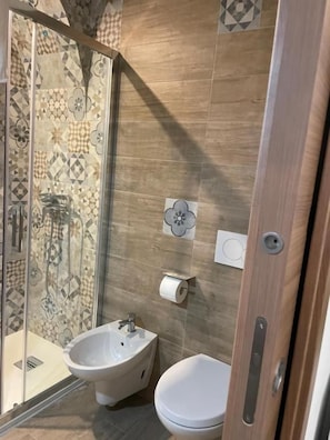 A bathroom with a bidet, toilet, and patterned shower enclosure. - L angolo delle bugie (Turi)