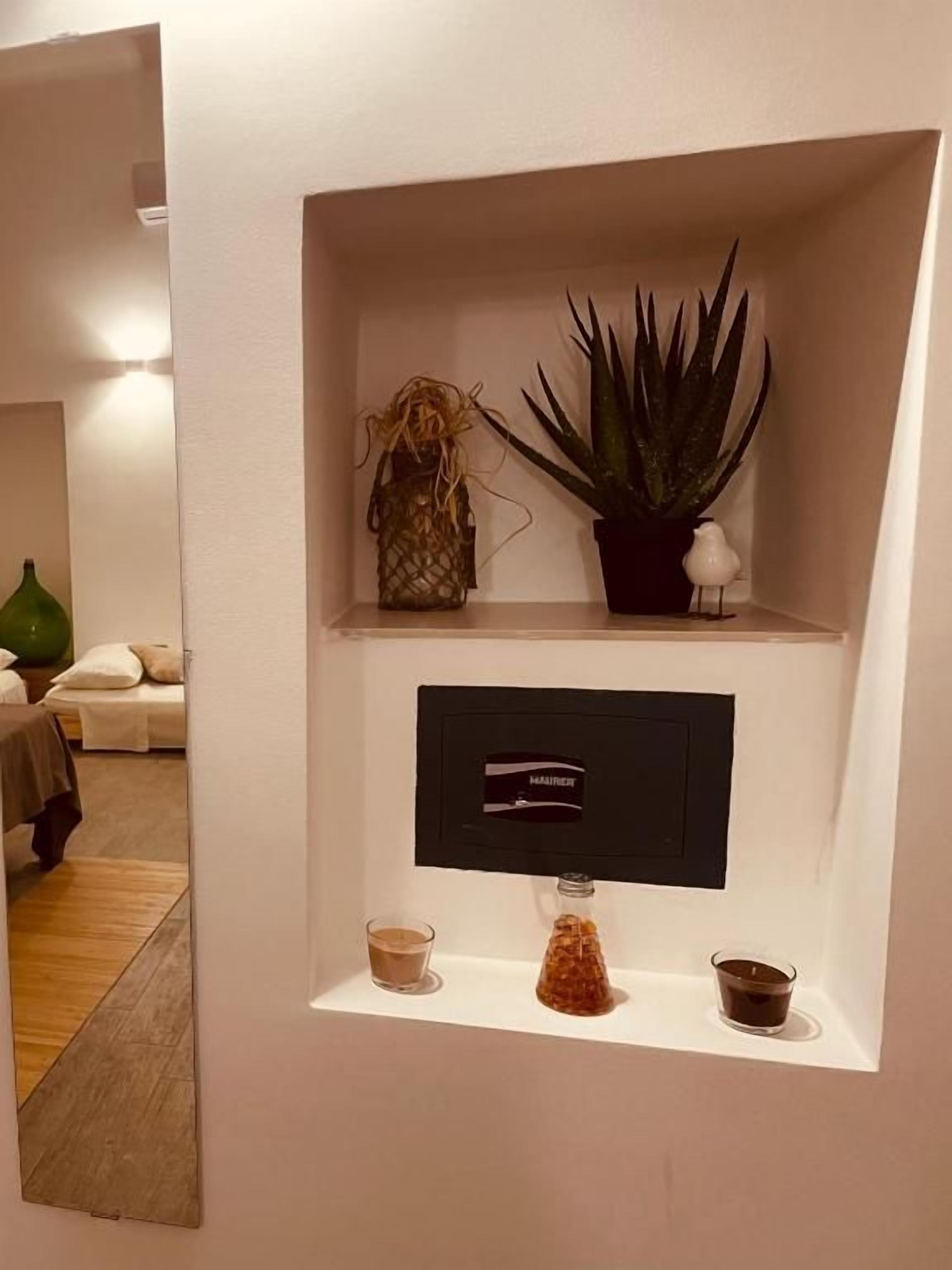 Una repisa con una planta en maceta, un adorno, un pequeño jarrón y un objeto enmarcados.
