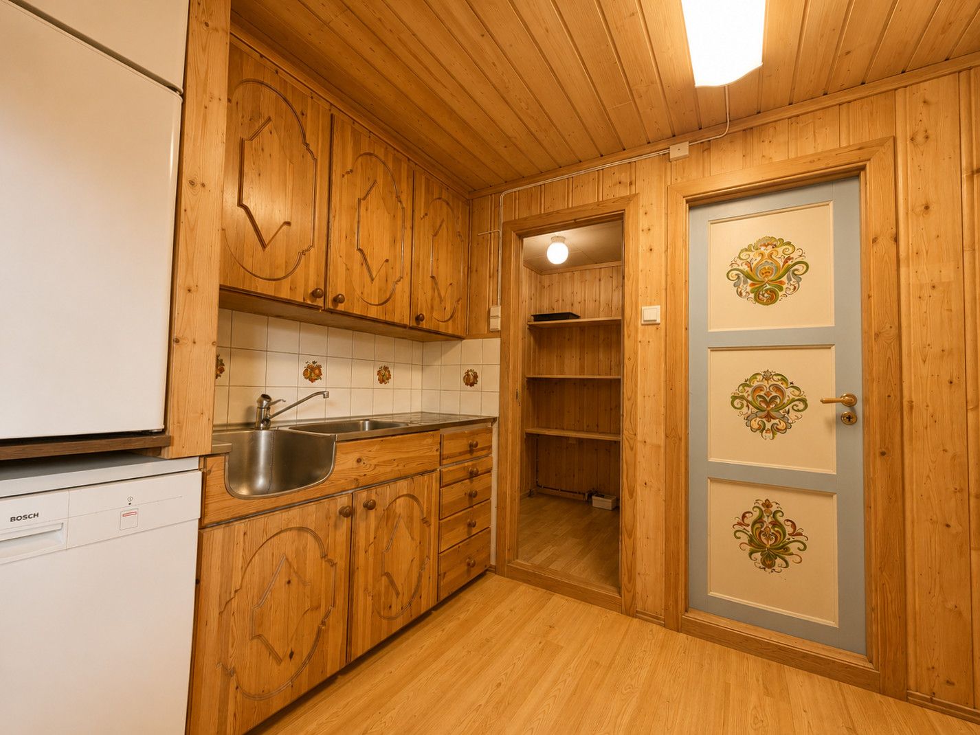 Een keuken met houten kastjes, een Bosch vaatwasser en een spoelbak.
