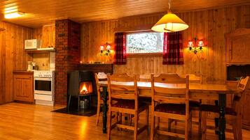 Un accogliente interno in legno con camino, tavolo da pranzo e sedie.