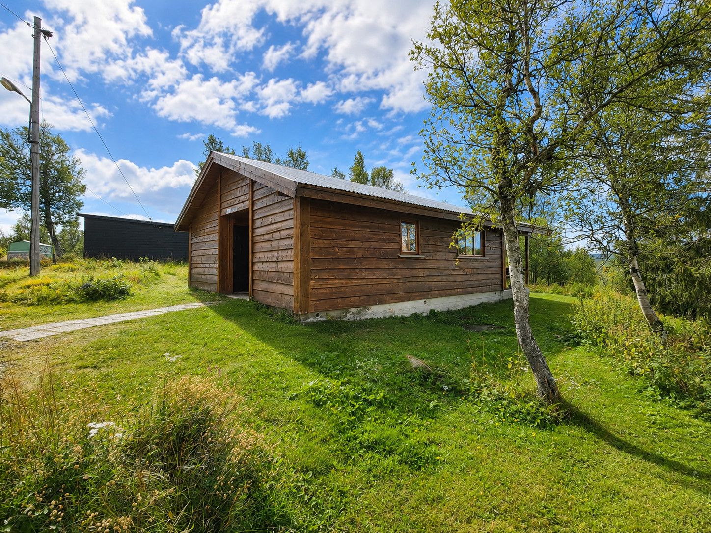 Une cabane en bois avec un toit en pente, une porte et une fenêtre.