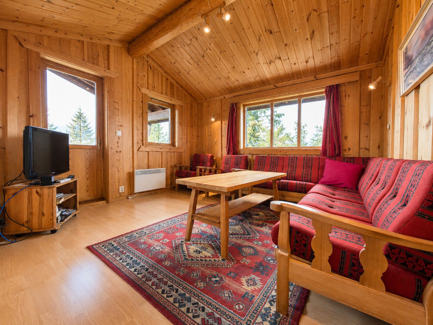 Een houten cabin met een bank, tafel en televisie.