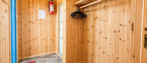 A wooden interior with a fire extinguisher, a red mat, and a coat rack.