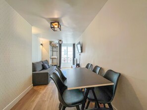 Ein modernes Interieur mit Esstisch, Stühlen, einer Couch und einem an der Wand befestigten Fernseher.