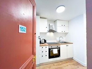 A modern kitchen with white cabinets, a stainless steel range hood, a built-in oven, and a wooden countertop. - 152 - Urban Cosy Flat in Paris (París)