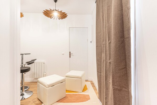 Et moderne, lyst værelse med en hvid dør, en radiator, en stol og en lille skammel.