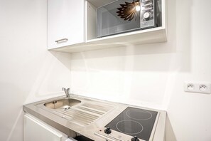 A compact kitchenette with a stainless steel sink, a microwave, and a built-in stove. - 147 - Urban Cosy Flat in Paris (París)