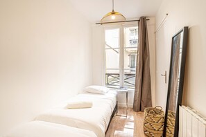A bedroom with a bed, a window, a radiator, and a woven basket. - 147 - Urban Cosy Flat in Paris (París)