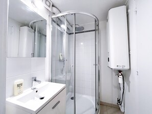 Ein modernes Badezimmer mit einer gläsernen Duschkabine, einem weißen Waschbecken und einer eingebauten Heizung.