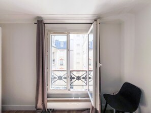 Ein Zimmer mit Fenster, Stuhl und Heizkörper.
