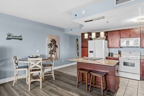 Une cuisine moderne avec un îlot central, des chaises en bois, une table à manger et un four à micro-ondes.