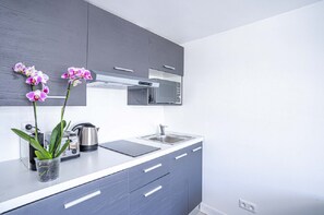A modern kitchen with grey cabinets, a stainless steel kettle, and a sink. - 145 - Urban Pretty Studio in Center of Paris (París)