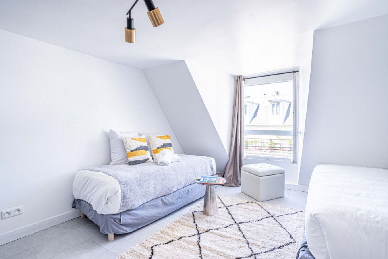 Ein modernes Schlafzimmer mit einem Bett, einem Nachttisch und Blick auf Gebäude durch ein Fenster.