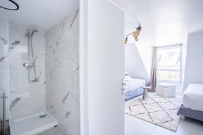 A modern bathroom with a shower, a visible toilet, and a bedroom with a bed, a nightstand, and a window. - 145 - Urban Pretty Studio in Center of Paris (París)