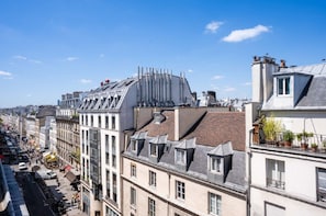 A cityscape with multi-story buildings, including a building with a distinctive curved roof and another with a flat roof. - 145 - Urban Pretty Studio in Center of Paris (París)