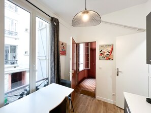 A room with a white table, a hanging light fixture, a door with a Mickey Mouse poster, and a checkered floor. - 146 - Urban Cosy Flat in Paris (París)
